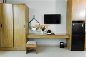A compact hotel room with a kitchenette, a bed, a TV, and a small seating area.