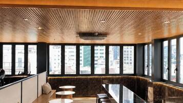 A modern interior with a long dining table, multiple seating options, and large windows offering city views.