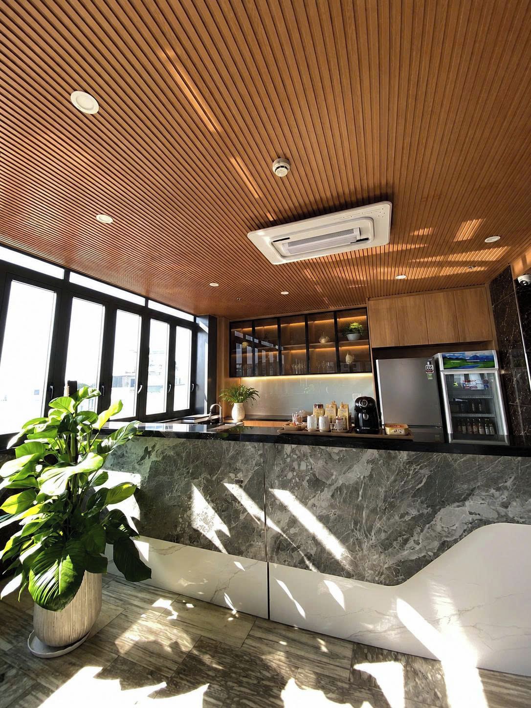 A modern kitchen with a wooden ceiling, marble countertops, and a built-in refrigerator.