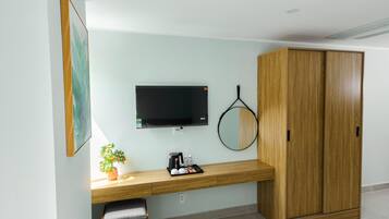 A modern room with a wooden desk, a television mounted on the wall, a wardrobe, and a potted plant.