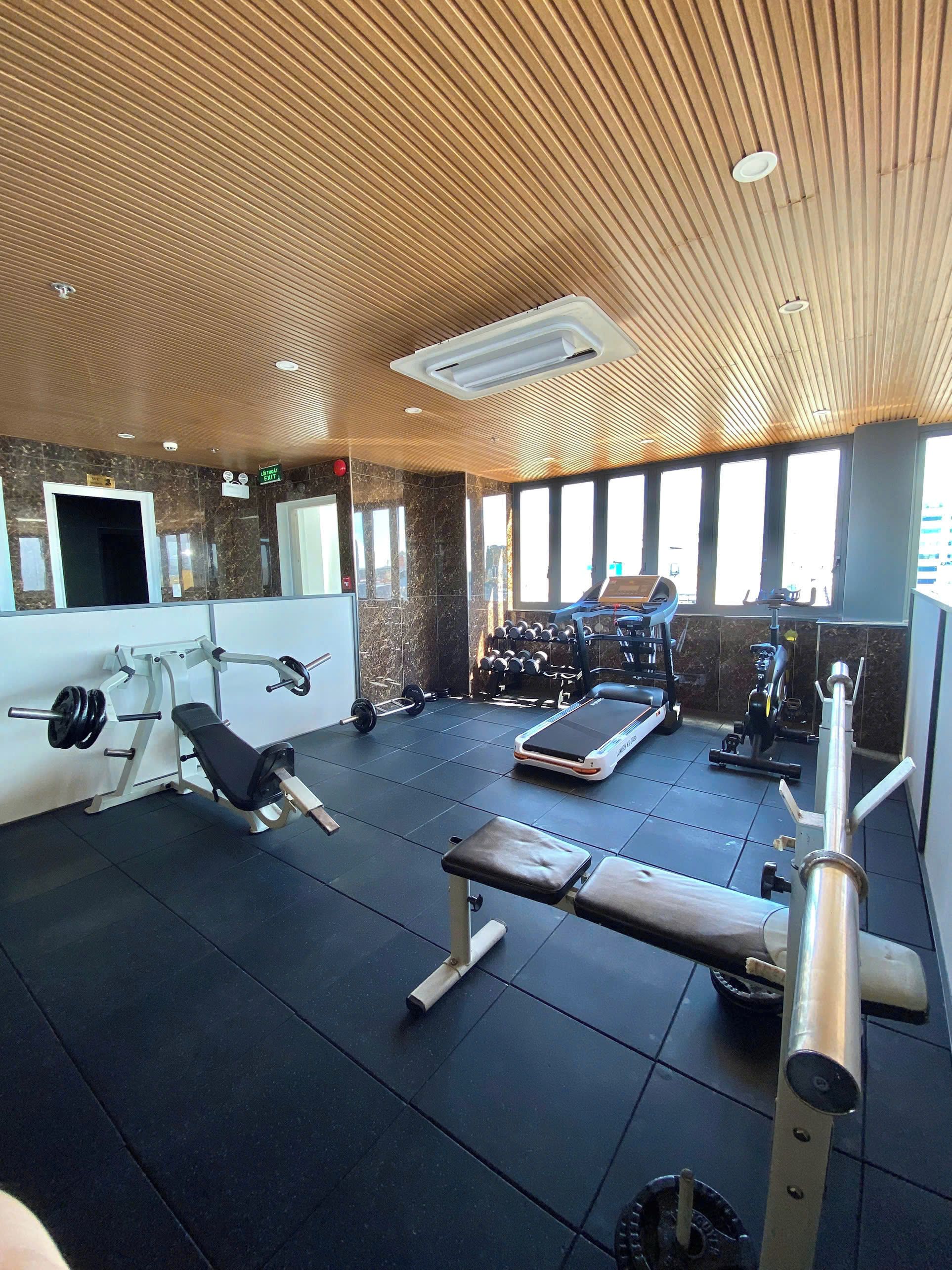 A gym with exercise equipment, a bench, and a wall-mounted TV.