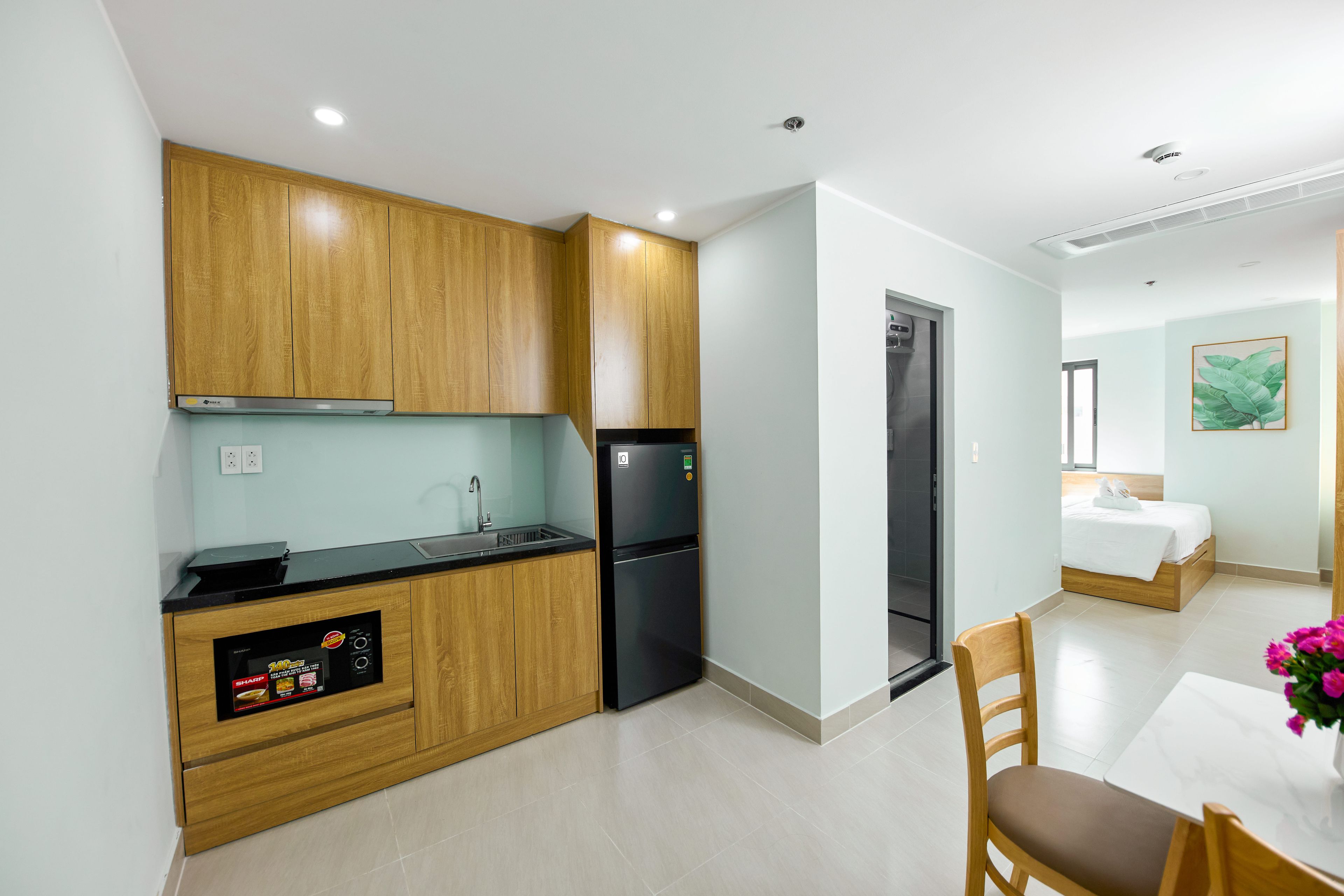 A compact kitchen with wooden cabinets, a black refrigerator, and a built-in oven.