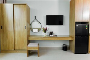 Una kitchenette moderna con refrigerador integrado, televisor de pantalla plana, un mueble de madera, un pequeño banco y una cafetera.