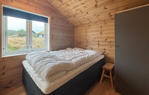 Un lit simple dans une pièce aux murs en bois et dotée d’une fenêtre.