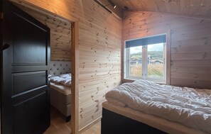 A bedroom with a bed, a wardrobe, and a window with a view of houses and grass. - Stunning home in Tjørhom with sauna (Tjørhom)