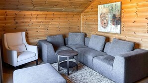 Una habitación acogedora con un sofá seccional gris, un sillón blanco y una pequeña mesa redonda.