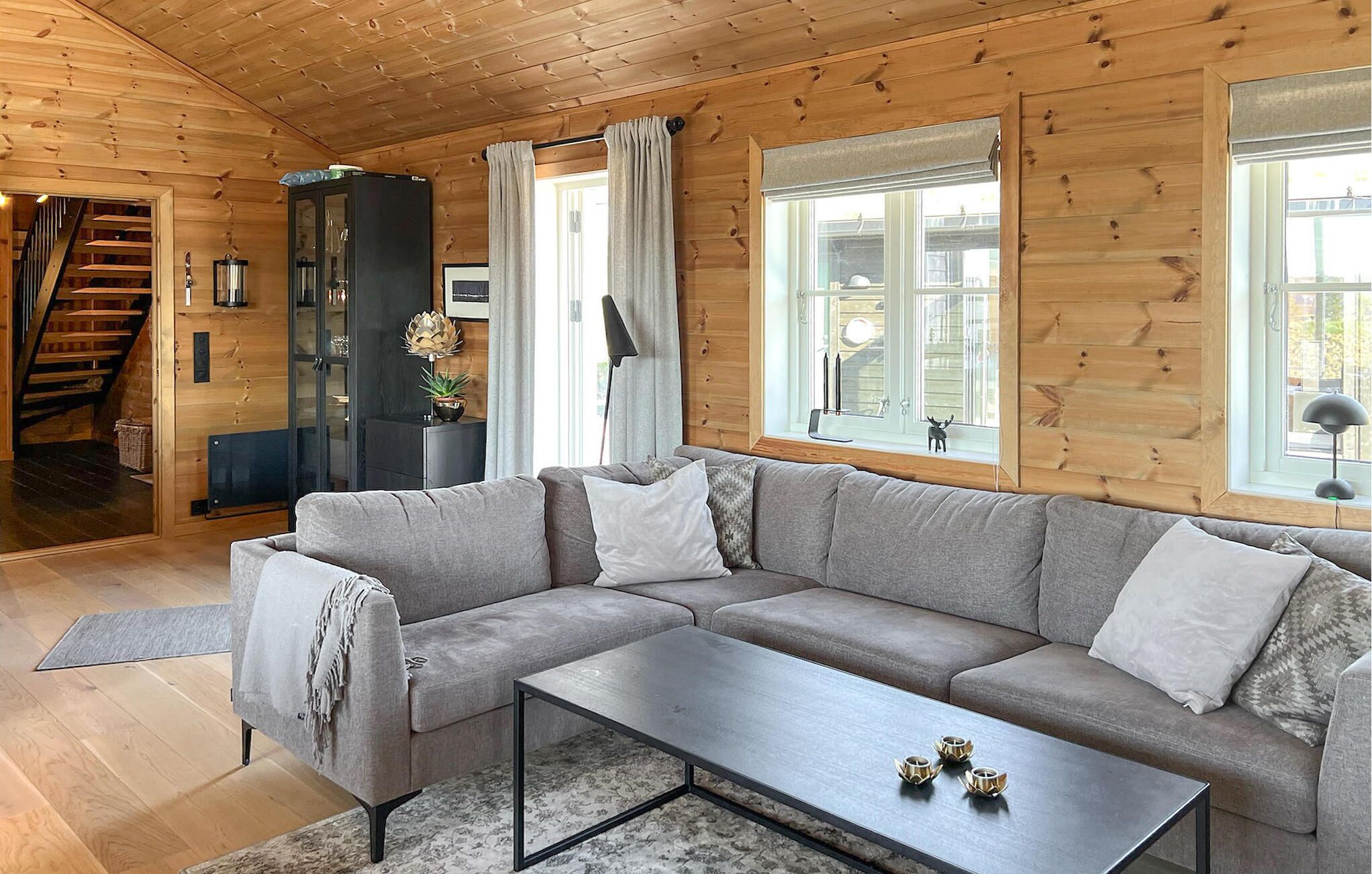 A modern living room with a grey sectional sofa, a coffee table, and a staircase leading to another level.