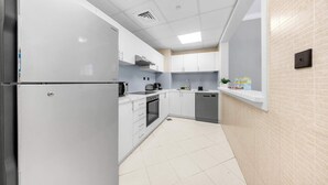 Una cucina compatta con mobili bianchi, forno integrato e lavastoviglie.