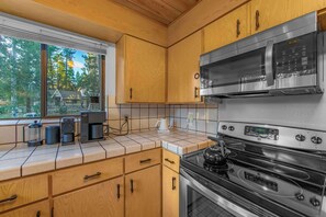 A kitchen with wooden cabinets, a stainless steel microwave, and an oven.