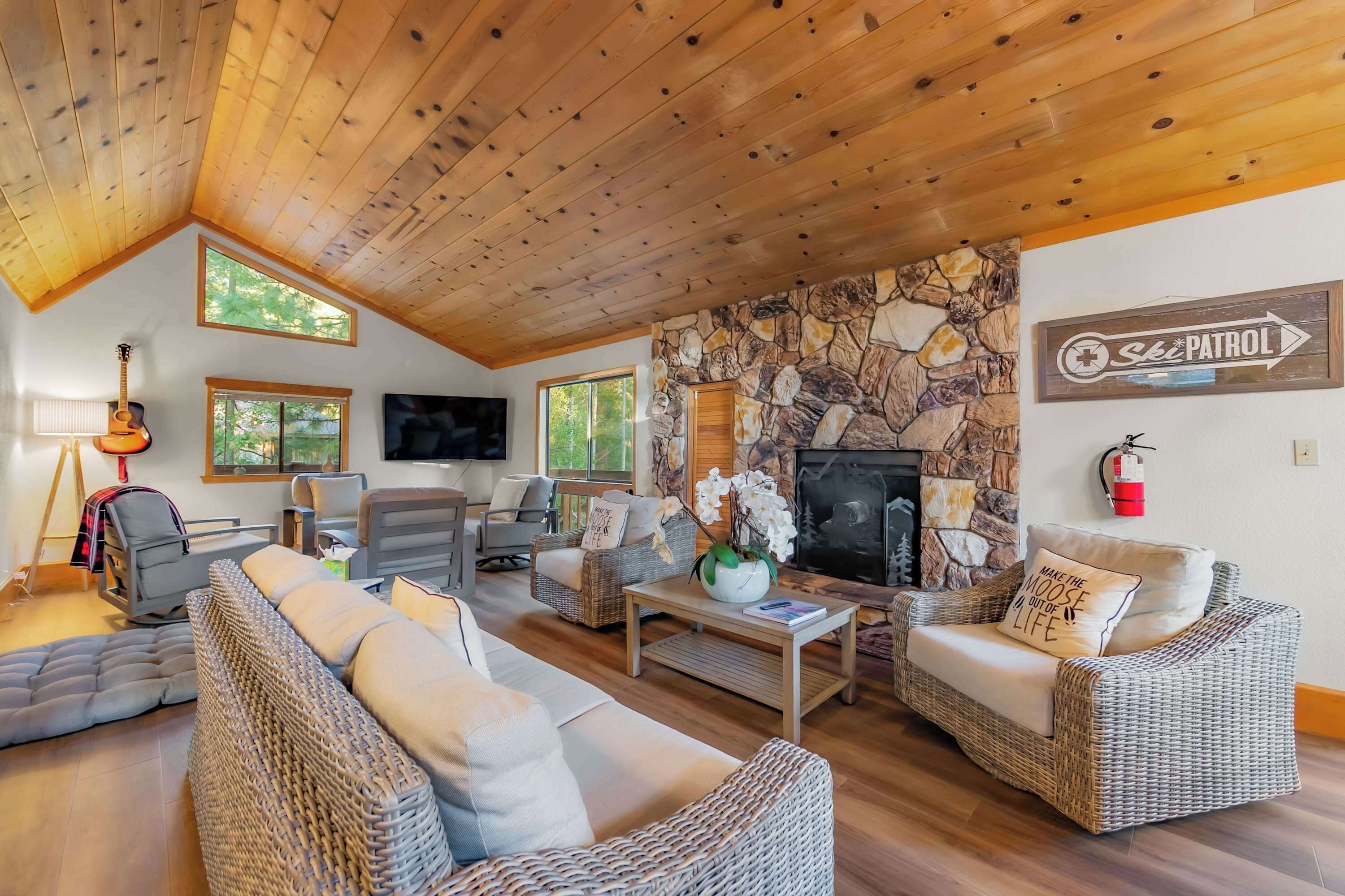A cozy living room with a stone wall, wicker furniture, a fireplace, and a ski patrol sign.