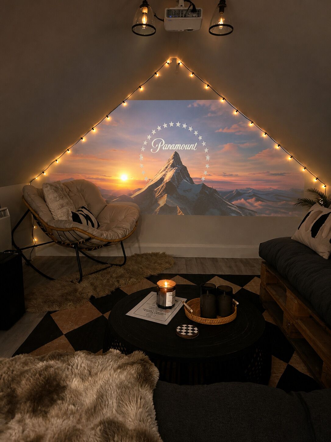 Une pièce chaleureuse avec vue sur la montagne, décorée de guirlandes lumineuses, équipée d’un projecteur et dotée d’un coin salon confortable.