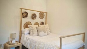 Un dormitorio con cama de madera, una mesita de noche, una lámpara y adornos en la pared.