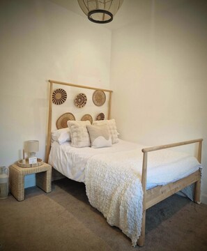 Un dormitorio con cama de madera, una mesita de noche, una lámpara y adornos en la pared.