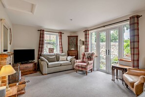 A living room with a sofa, armchair, television, and a fireplace. - Host & Stay | Tusker House (Wells-next-the-Sea)