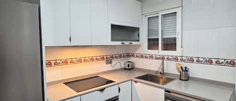 Una cocina moderna con armarios blancos, horno empotrado, lavavajillas y microondas.