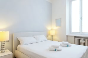 A hotel room with a bed, two bedside lamps, a window, and a radiator. - Apartment in Milan with 2 bedrooms sleeps 4 (Milan)