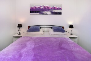 A bedroom with a bed, two bedside lamps, a wall-mounted painting, and a white nightstand. - Island Krk Villa Niko PET FRIENDLY 200meters from hidden sandy beachPET FRIENDLY (Krk)