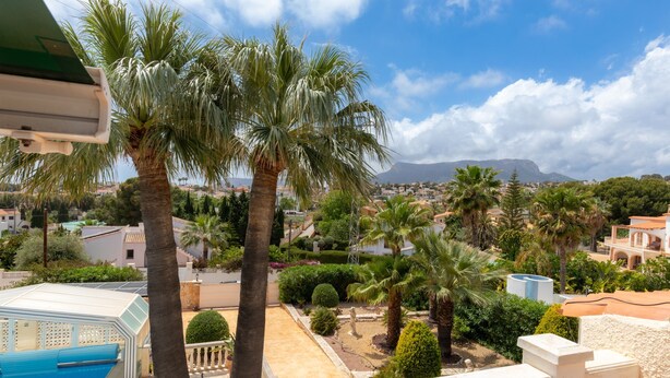 A residential area with palm trees, a swimming pool, and a view of a mountain in the distance. - Casa Nuestro Sue o Para 4 Personas (Calpe)