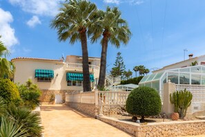 A Mediterranean-style villa with a stone facade, a glass conservatory, and a paved courtyard. - Casa Nuestro Sue o Para 4 Personas (Calpe)