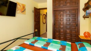 A hotel room with a bed, a television mounted on the wall, and a door with a coat rack. - Casa Nuestro Sue o Para 4 Personas (Calpe)