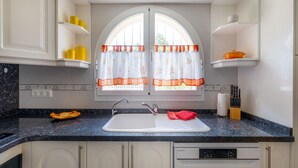 A kitchen with a double sink, white cabinets, a dish rack, and a Sharp dishwasher. - Casa Nuestro Sue o Para 4 Personas (Calpe)
