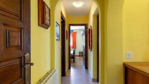 A hallway with a wooden door, a radiator, and a tiled floor leading to a room with a bed and curtains. - Casa Nuestro Sue o Para 4 Personas (Calpe)