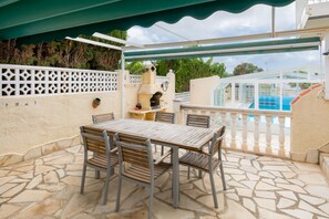 An outdoor patio with a table and chairs, a stone floor, and a view of a pool. - Casa Nuestro Sue o Para 4 Personas (Calpe)