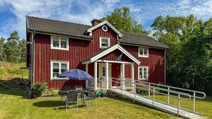 A red wooden house with a porch, a small table with chairs, and a wheelchair ramp. - Cozy home in Tranås with WiFi (Tranås)