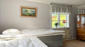 A bedroom with a bed, a dresser, a window with a view, and a painting on the wall. - Cozy home in Tranås with WiFi (Tranås)