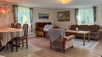 A cozy living room with a dining table, two sofas, a patterned rug, and a chandelier.