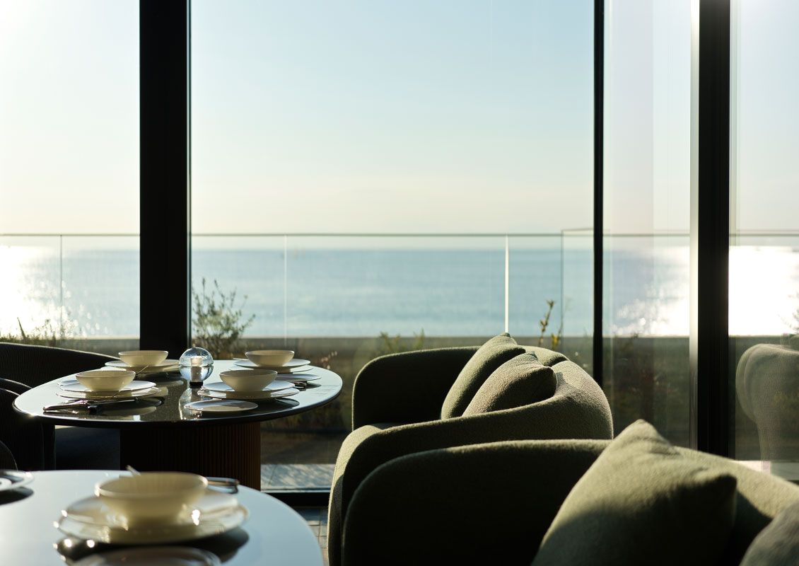A dining area with a table set for two, overlooking a body of water.