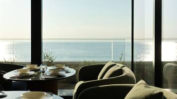 A dining area with a table set for two, overlooking a body of water.
