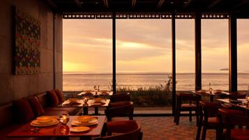 A restaurant with a view of the sea, featuring tables and chairs arranged for dining.