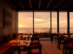 A restaurant with a view of the sea, featuring tables and chairs arranged for dining.