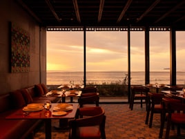 A restaurant with a view of the sea, featuring tables and chairs arranged for dining.