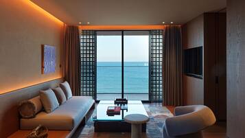 Una habitación de hotel moderna con sofá, una mesita de centro, una mesita auxiliar y vista al mar a través de amplias ventanas.