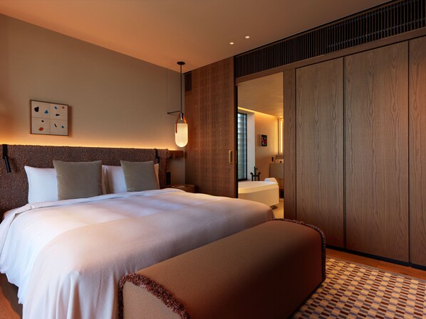 A hotel room with a large bed, a bedside table, a lamp, and a wardrobe.