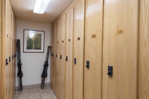 Eine Reihe von Holfachschränken, auf denen die Nummern 334 und 341 sichtbar sind, und ein gerahmtes Bild von einem Wald an der Wand.