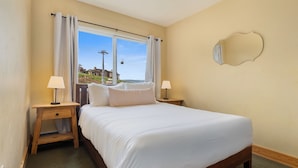 A bedroom with a large bed, two bedside tables with lamps, a window with curtains, and a wall-mounted mirror. - Ski In/Out|Hot Tub|Great Views|Walk to Base Area (Steamboat Springs)