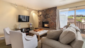 A living room with a stone fireplace, a flat-screen TV, and a sofa. - Ski In/Out|Hot Tub|Great Views|Walk to Base Area (Steamboat Springs)