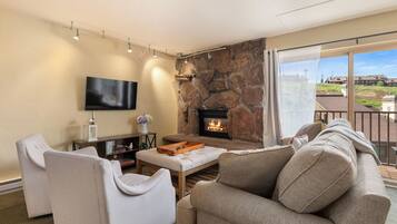 A living room with a stone fireplace, a flat-screen TV, and a sofa.