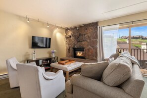 Ein Wohnzimmer mit Kamin aus Stein, einem Flachbildfernseher und einem Sofa.