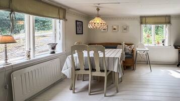 A dining area with a table set for four, a bench, and a high ceiling with a hanging light fixture.