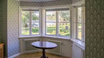 Quarto com janela panorâmica, radiador e uma mesa.