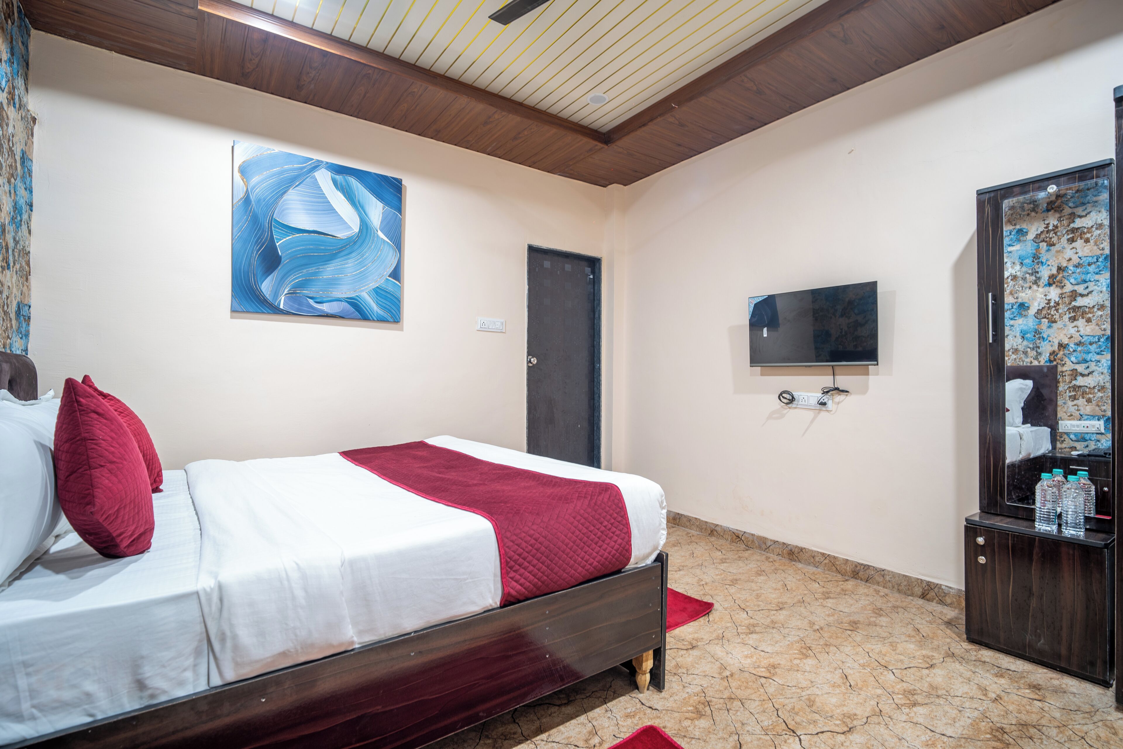 Una habitación de hotel con una cama, un cuadro, un televisor y un espejo.
