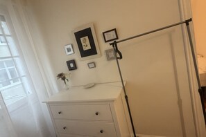 A white dresser with drawers, a small vase with dried flowers, and several framed pictures on the wall. - 1A172 Quiet Apartment in Gijón (Gijón)