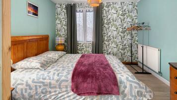 A bedroom with a bed, a wooden headboard, a radiator, and a window with curtains.