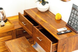 A wooden desk with a white vase, a yellow flower, a remote control, and a black object on it. - Ubud Heritage Stay (Gianyar)