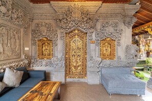 An ornate room with a sofa, a coffee table, and a sign indicating 'ROOM 105'. - Ubud Heritage Stay (Gianyar)