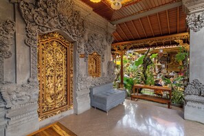 An ornate room with intricate carvings, a bench, and a sign indicating room number 105. - Ubud Heritage Stay (Gianyar)